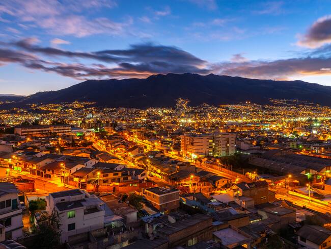 The skyline of Quito at sunset with night lights with the Pichincha volcano, Ecuador.