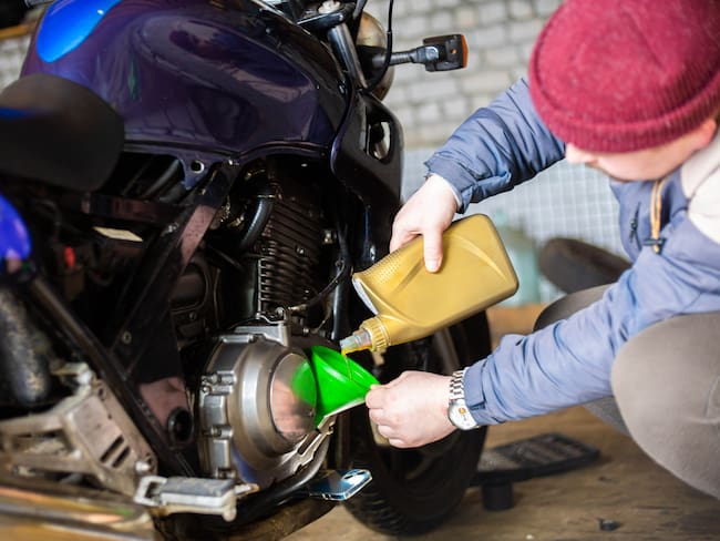 Hombre cambiando el aceite a una motocicleta - Foto vía Getty Images