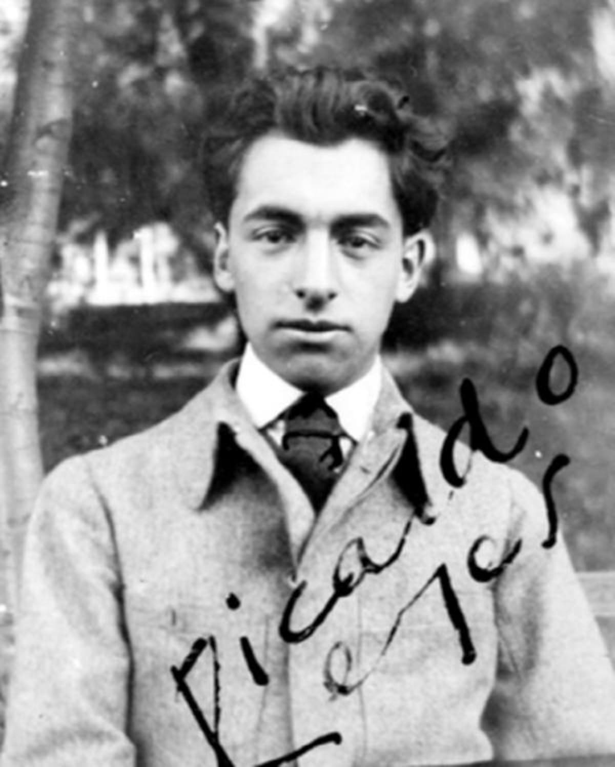 Fotografía blanco negro del joven Pablo Neruda (1904–1973) de medio cuerpo y de frente. Aparece Neruda serio frente a la cámara, hasta la mitad del pecho. Viste chaqueta clara y corbata oscura. Tiene el cabello corto penado hacia atrás levemente levantado. En el lado derecho inferior firme diagonalmente “Ricardo Reyes”