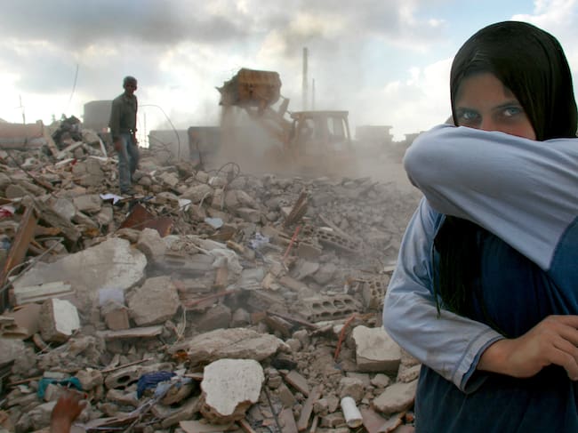 Lebanon, Sidiken, Girl in destroyed town covering mouth from ashes, portrait: Getty Images