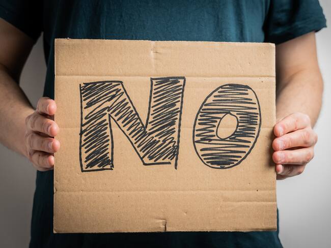 Anonymous protester showing sign with word NO, symbolizing rejection, disagreement, or resistance