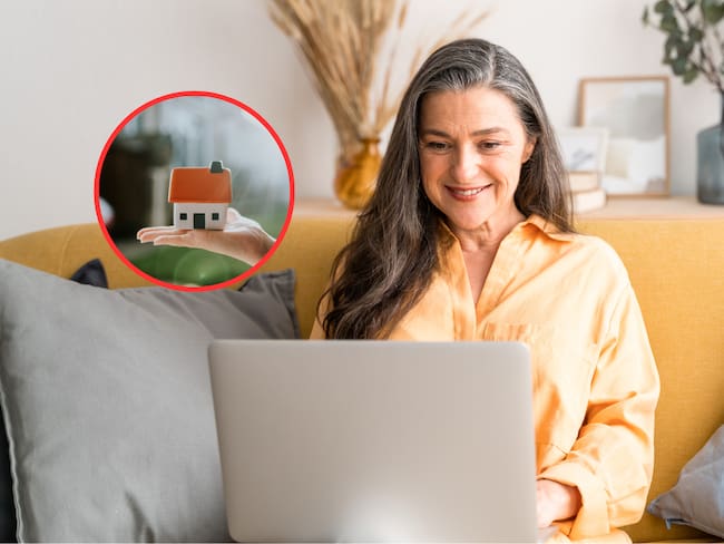 Mujer utilizando su computador portátil y de fondo una casa en tamaño miniatura (Fotos vía Getty Images)
