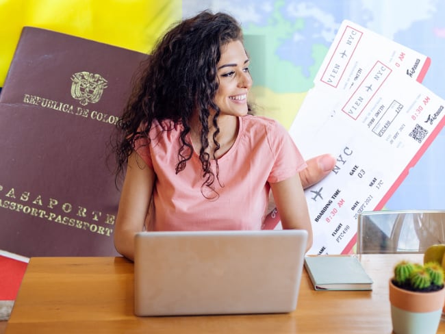 Mujer trabajando junto a pasaporte colombiano y tiquete de avión - Cortesía