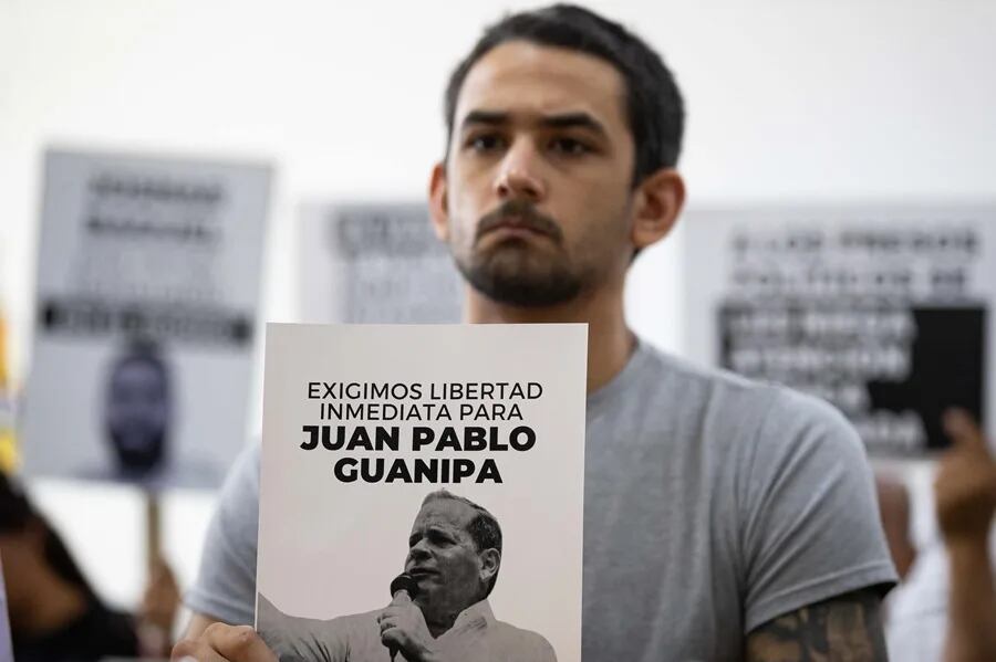 Imagen de referencia: Ramón Guanipa sostiene un cartel de su padre detenido, Pedro Guanipa, en una imagen reciente. EFE/Ronald Peña R