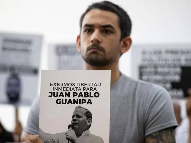 Imagen de referencia: Ramón Guanipa sostiene un cartel de su padre detenido, Pedro Guanipa, en una imagen reciente. EFE/Ronald Peña R