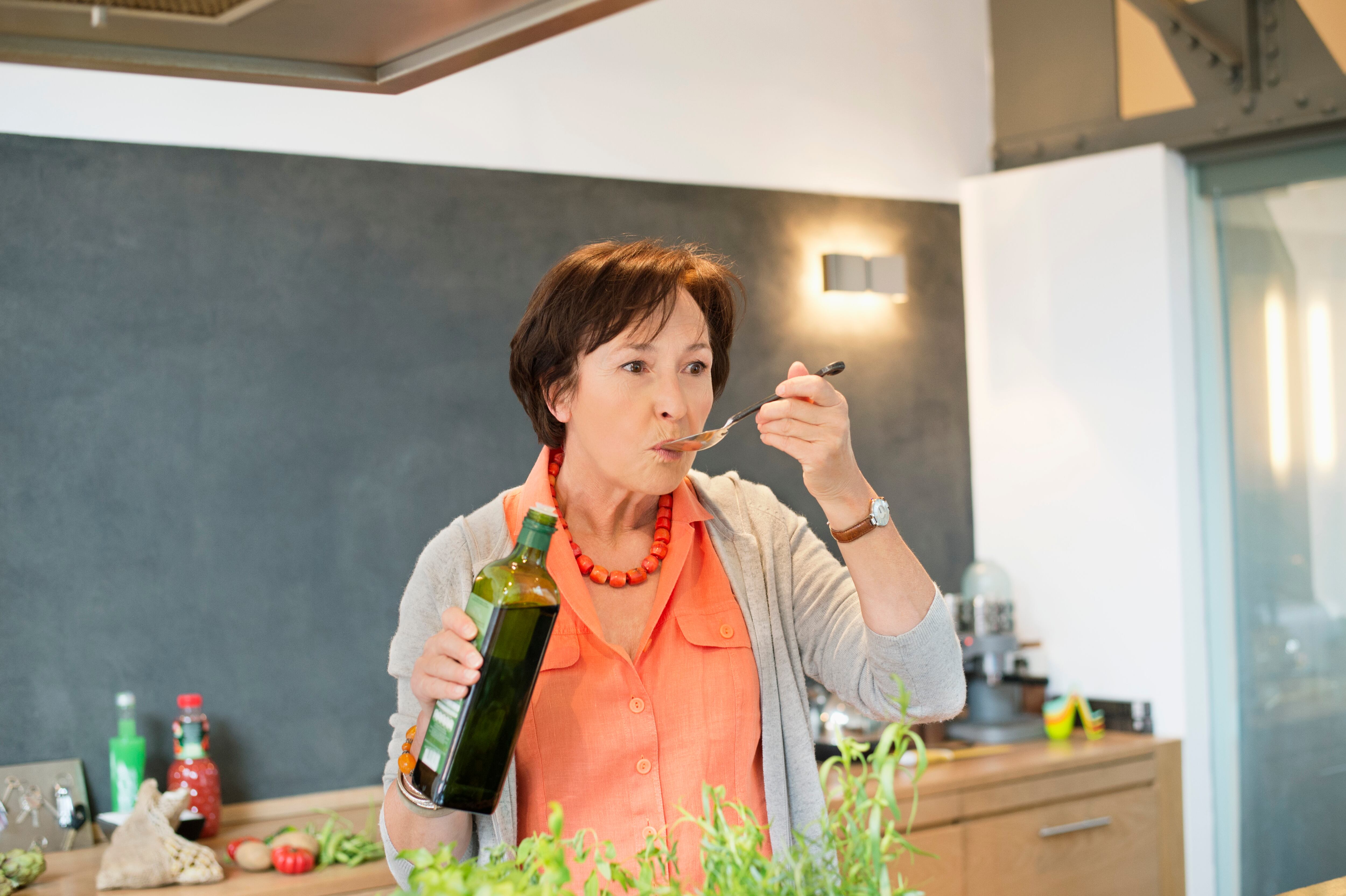 Mujer en la cocina comiendo una cucharada de aceite de oliva (Foto vía Getty Images)