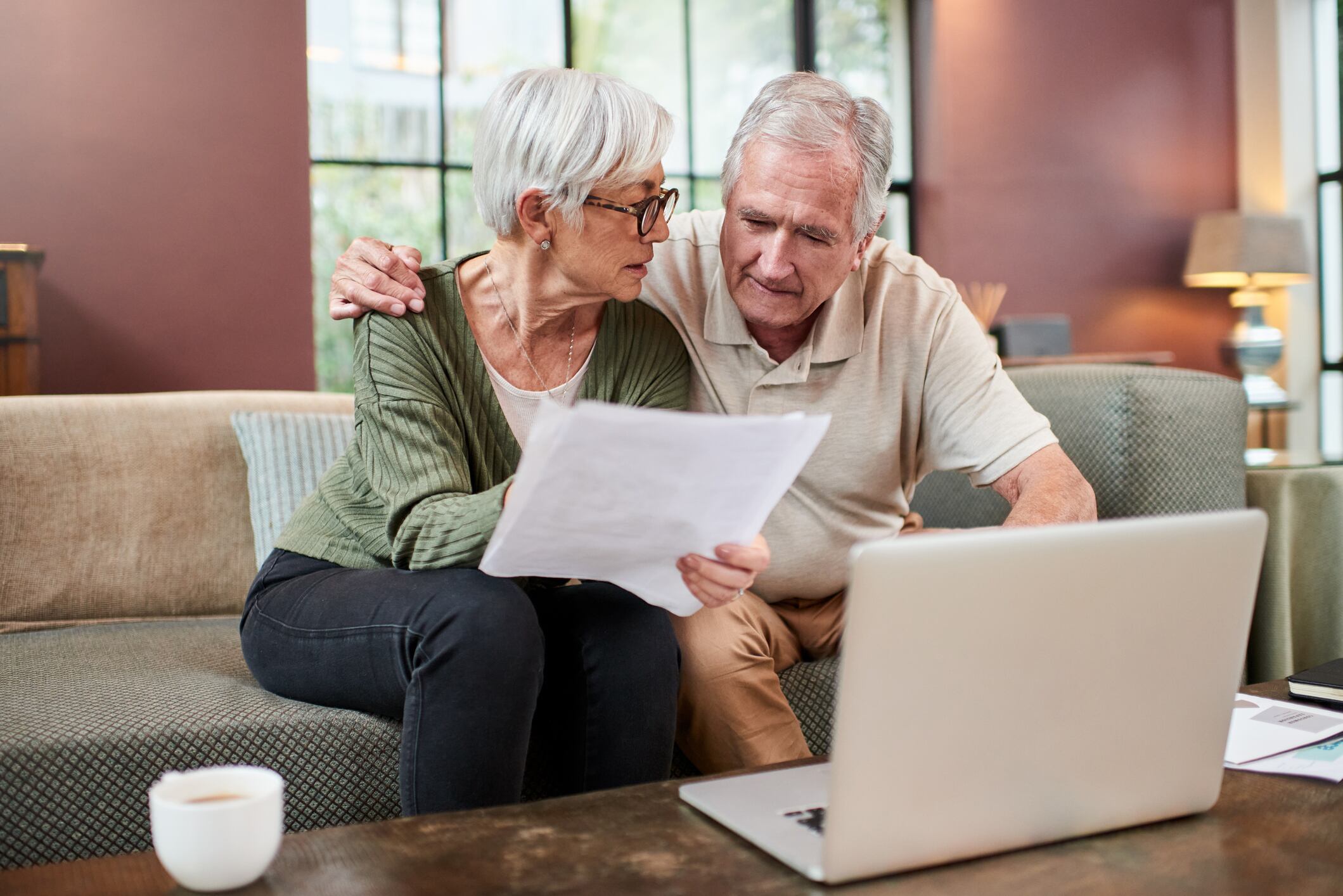 Pareja observando unos documentos mientras están sentados en un sofá (Getty Images)
