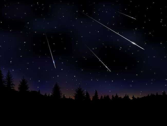 Lluvia de meteoritos perseidas que caen en el cielo nocturno oscuro vía Getty Images.