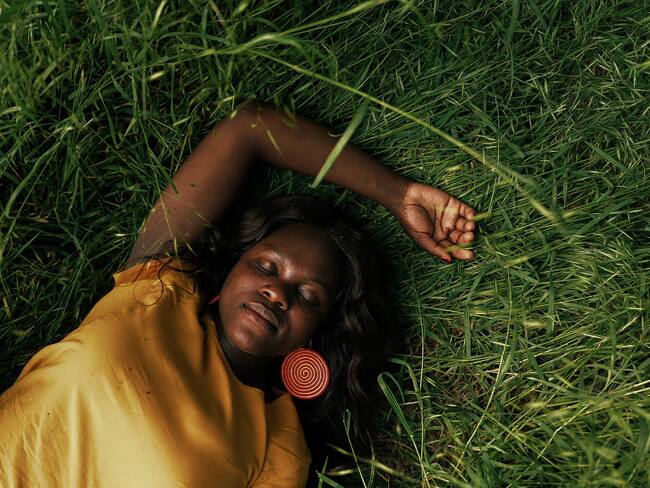 Mujer recostada en el pasto durmiendo (Getty Images)