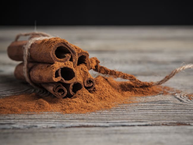Canela entera atada, sobre canela en polvo. (Foto: Getty Images)