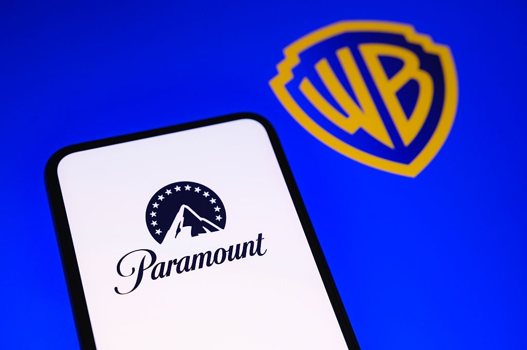 The Paramount logo is displayed on a smartphone screen with the Warner Bros. logo in the background in Creteil, France, on September 22, 2026, as Paramount Skydance reached a settlement with 12 state attorneys general who had challenged its acquisition of Warner Bros. Discovery. (Photo by Samuel Boivin/NurPhoto via Getty Images)