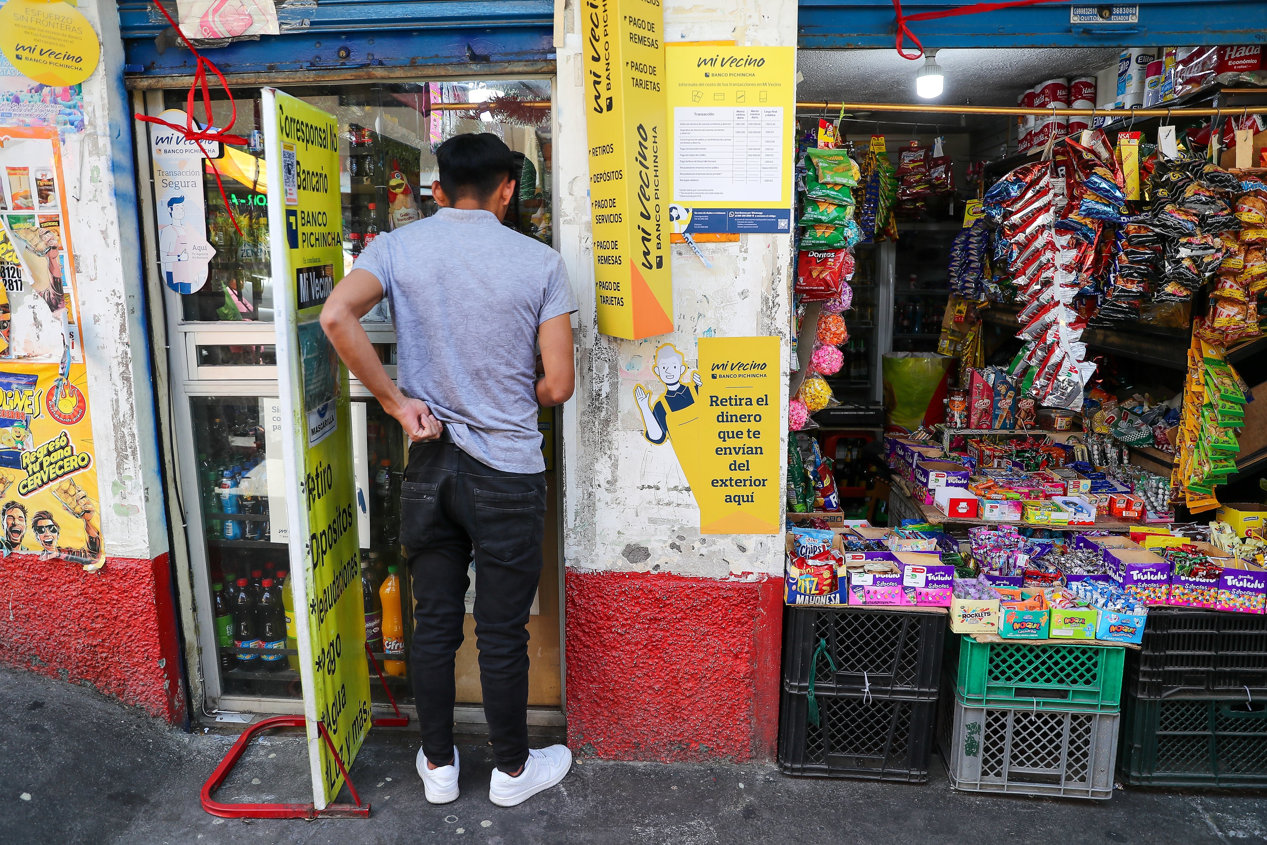 AME310. QUITO (ECUADOR), 16/09/2024.- Fotografía del 12 de septiembre de 2024 de un ciudadano siendo atendido en una agencia multipagos del Banco del Pichincha, en Quito (Ecuador). Los pequeños negocios de barrio como comercios, farmacias, tiendas de alimentos o bazares han llevado a que por primera vez un banco en Ecuador alcance el hito de tener presencia física en todo el territorio nacional, al estar presente en los 221 cantones (municipios) del país y llevar sus servicios a las zonas más recónditas y aisladas mediante conexión satelital. EFE/ José Jácome