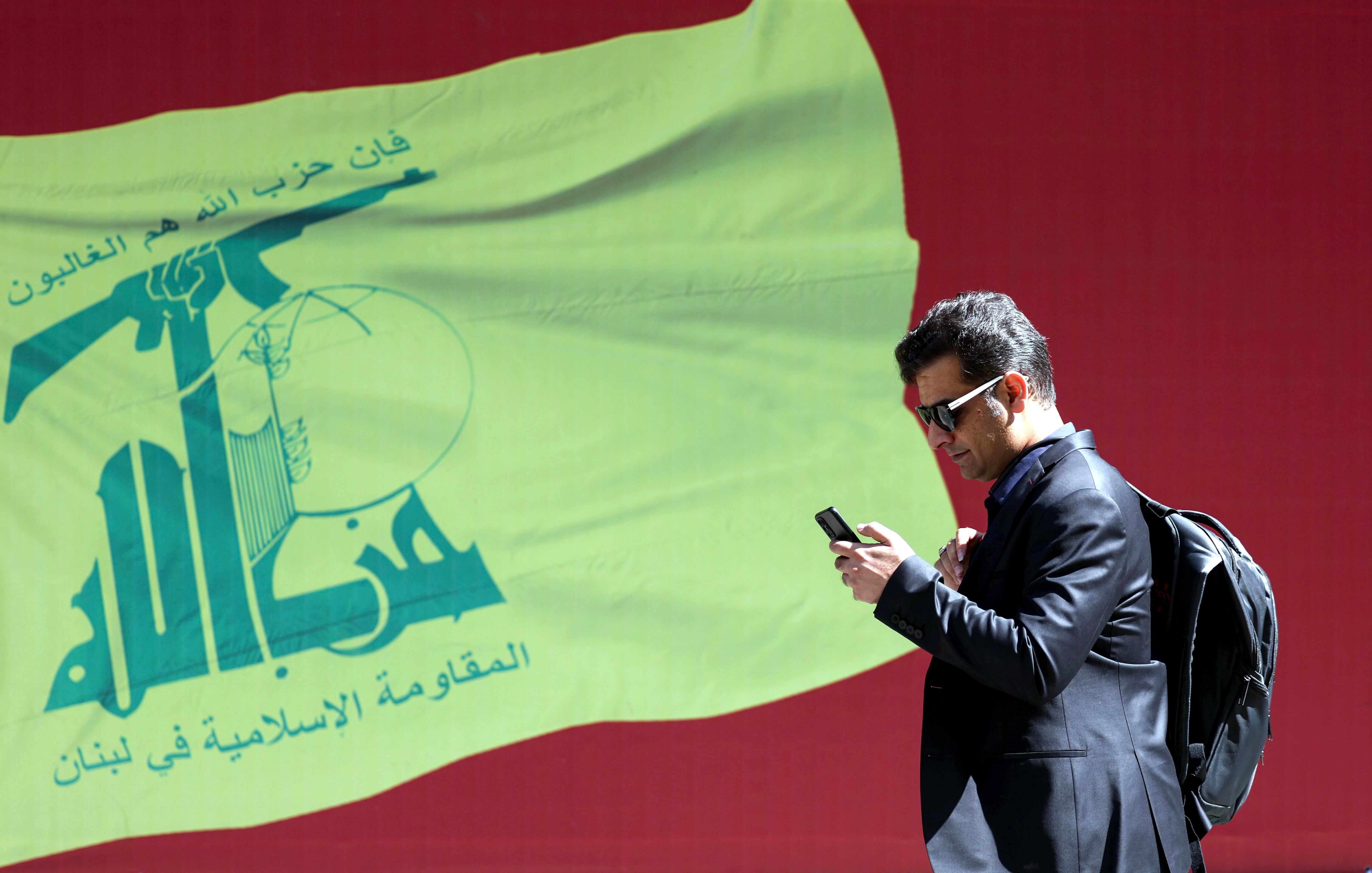 Hombre iraní camina frente a una bandera de Hezbolá en las calles de Teherán.
 EFE/EPA/ABEDIN TAHERKENAREH