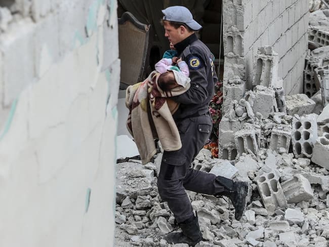 Un voluntario de los Cascos Blancos rescata a un bebé tras un ataque aéreo en Douma, Siria.