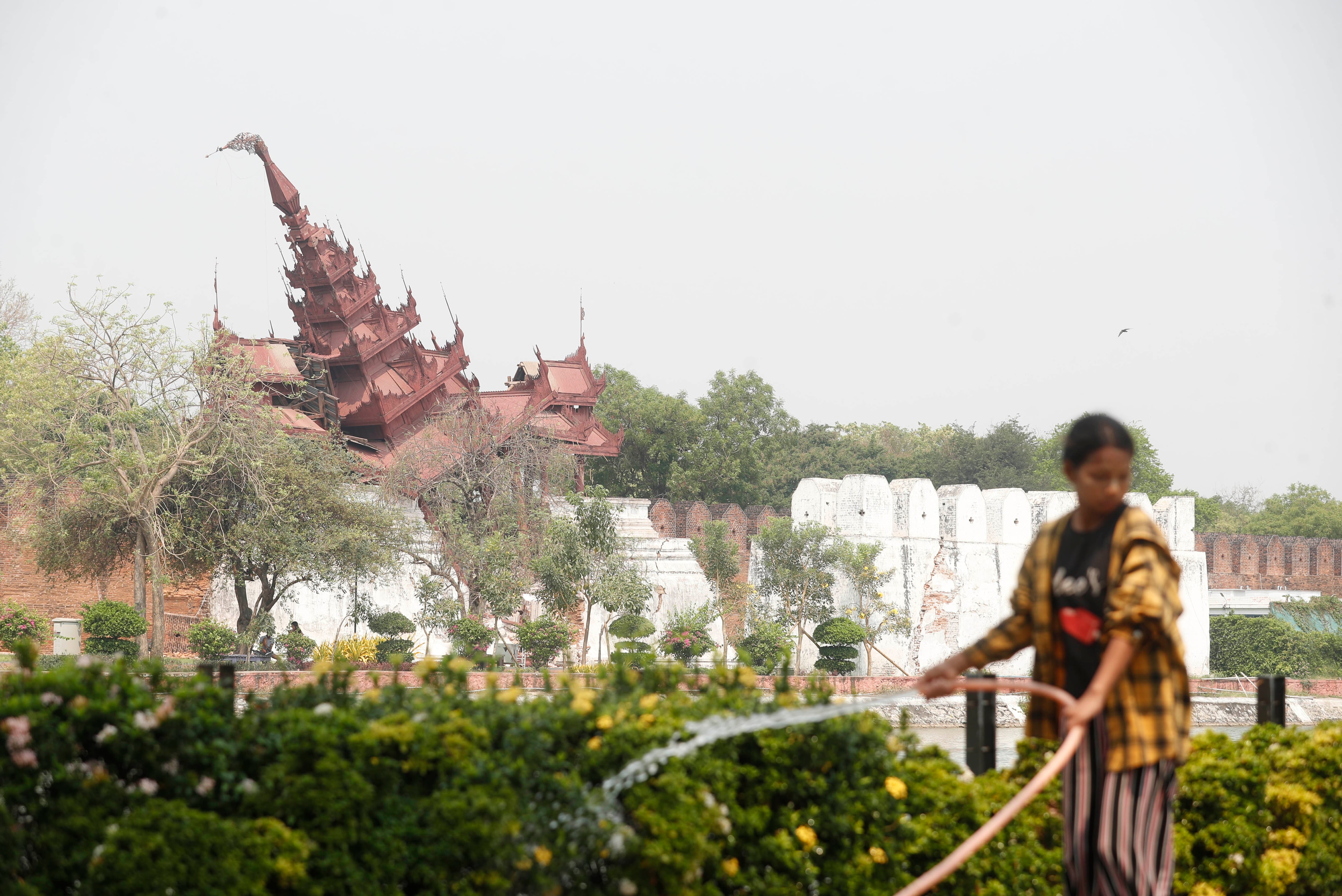 MANDALAY (Myanmar), 01/04/2025.- A woman pours water on plants in front of the damaged Mandalay palace in Mandalay, Myanmar, 01 April 2025. Myanmars military government has declared a week of national mourning after a 7.7-magnitude earthquake struck the country on 28 March, killing more than 2,000 people and injuring thousands, according to the government.  (Terremoto/sismo, Birmania) EFE/EPA/NYEIN CHAN NAING