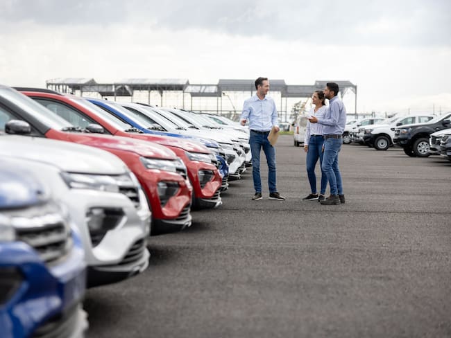Personas teniendo una conversación comercial de la venta de un carro en un consecionario de vehículos (Foto vía Getty Images)