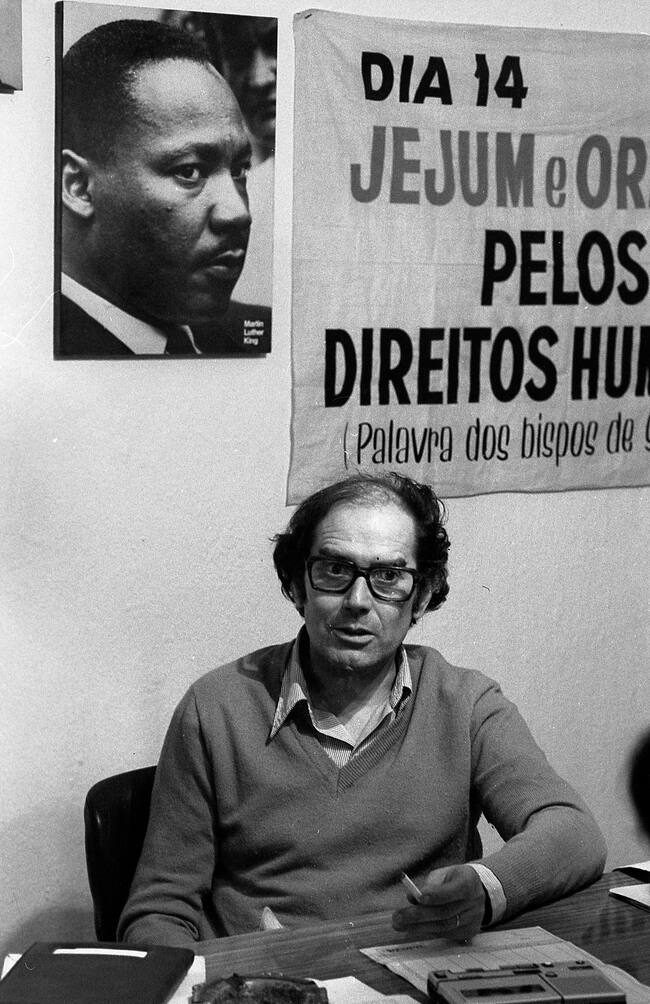 View of Nobel Prize-winning Argentine Human Rights activist, artist, and educator Adolfo Pérez Esquivel in his office, Buenos Aires, Argentina, 1980. On the wall behind him is a poster of Martin Luther King Jr. (Photo by Eduardo Comesaña/Getty Images)