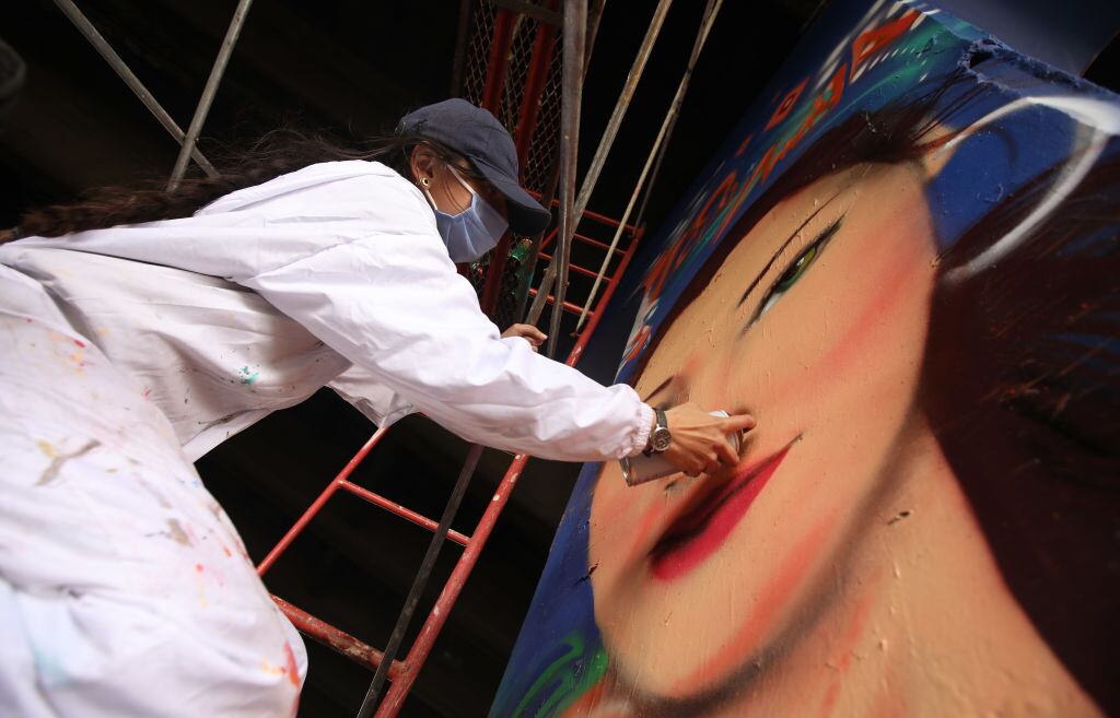 A graffiti artist paints a portrait of murdered nurse Lady Amaya under a bridge in Bogota, Getty Images.