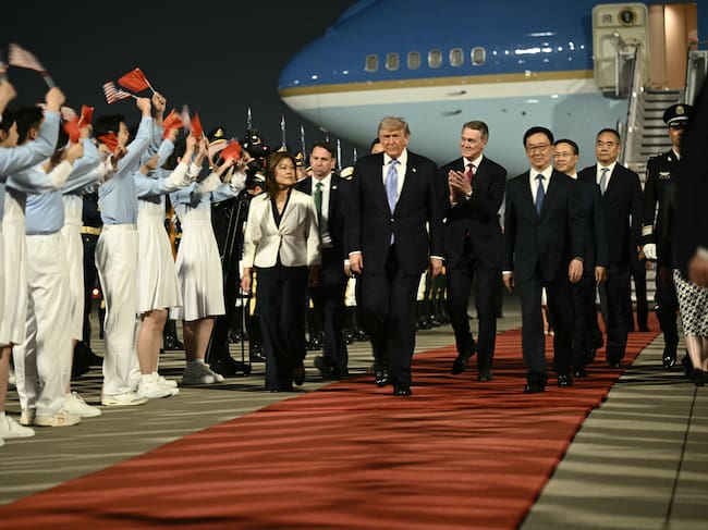US President Donald Trump (C), US Ambassador To china David Perdue (center-R) escorted by China's Vice President Han Zheng (R) are greeted by Chinese youth upon arriving at Beijing Capital Airport in Beijing on May 13, 2026. (Photo by Brendan SMIALOWSKI / AFP)