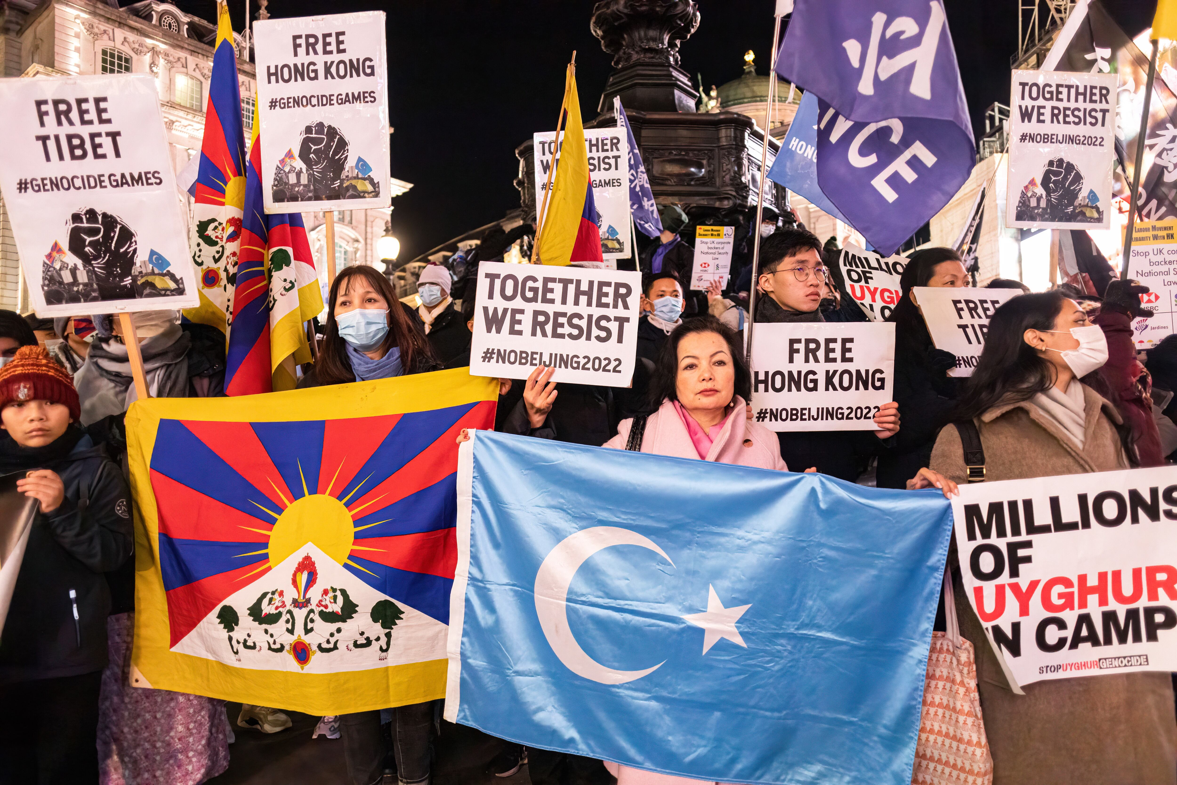 LONDON, UNITED KINGDOM - 2021/12/10: Rahima Mahmut (C), UK director of World Uyghur Congress and Executive Director of Stop Uyghur Genocide, holds the Uyghur flag while others raise their placards during a protest.In celebration of Human Rights Day on Dec. 10, various anti-Chinese Communist Party (anti-CCP) groups in London rallied at Piccadilly Circus and marched to 10 Downing Street. Hong Kongers, Tibetans, and Uyghurs came together to expose the CCP's attempts to oppress dissenting voices. Following a violent brawl in Chinatown on November 27, in which some Hong Kongers were injured. The rally was calling on Western nations to boycott the 2022 Beijing Winter Olympic games. (Photo by Belinda Jiao/SOPA Images/LightRocket via Getty Images)
