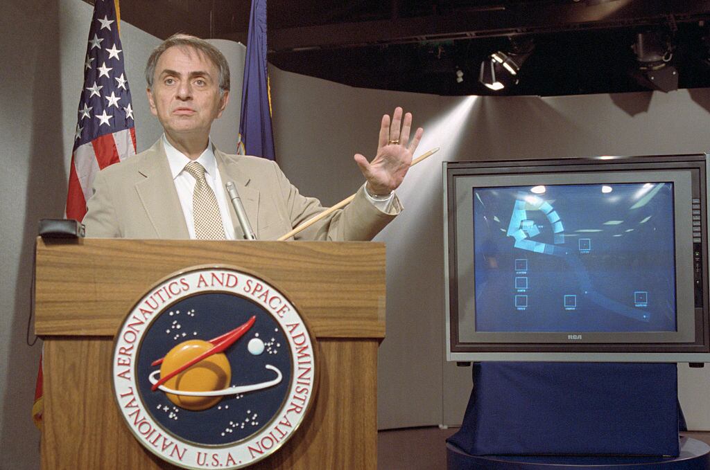 El astrónomo Carl Sagan habla en una conferencia de prensa donde la NASA puso a disposición las últimas fotografías tomadas por la Voyager 1, que muestran el sistema solar visto desde el exterior / Getty Images