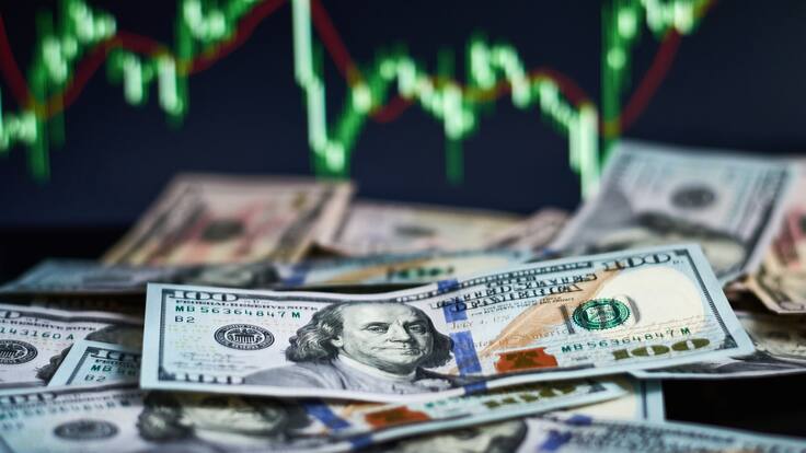 Billetes de 100 dólares con una gráfica representando los indicadores económicos (Foto vía GettyImages)