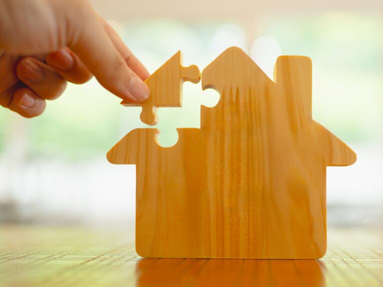 Una mano con la llave del mercado inmobiliario: Desbloquea tus sueños inmobiliarios con un rompecabezas de casas. (Getty Images)