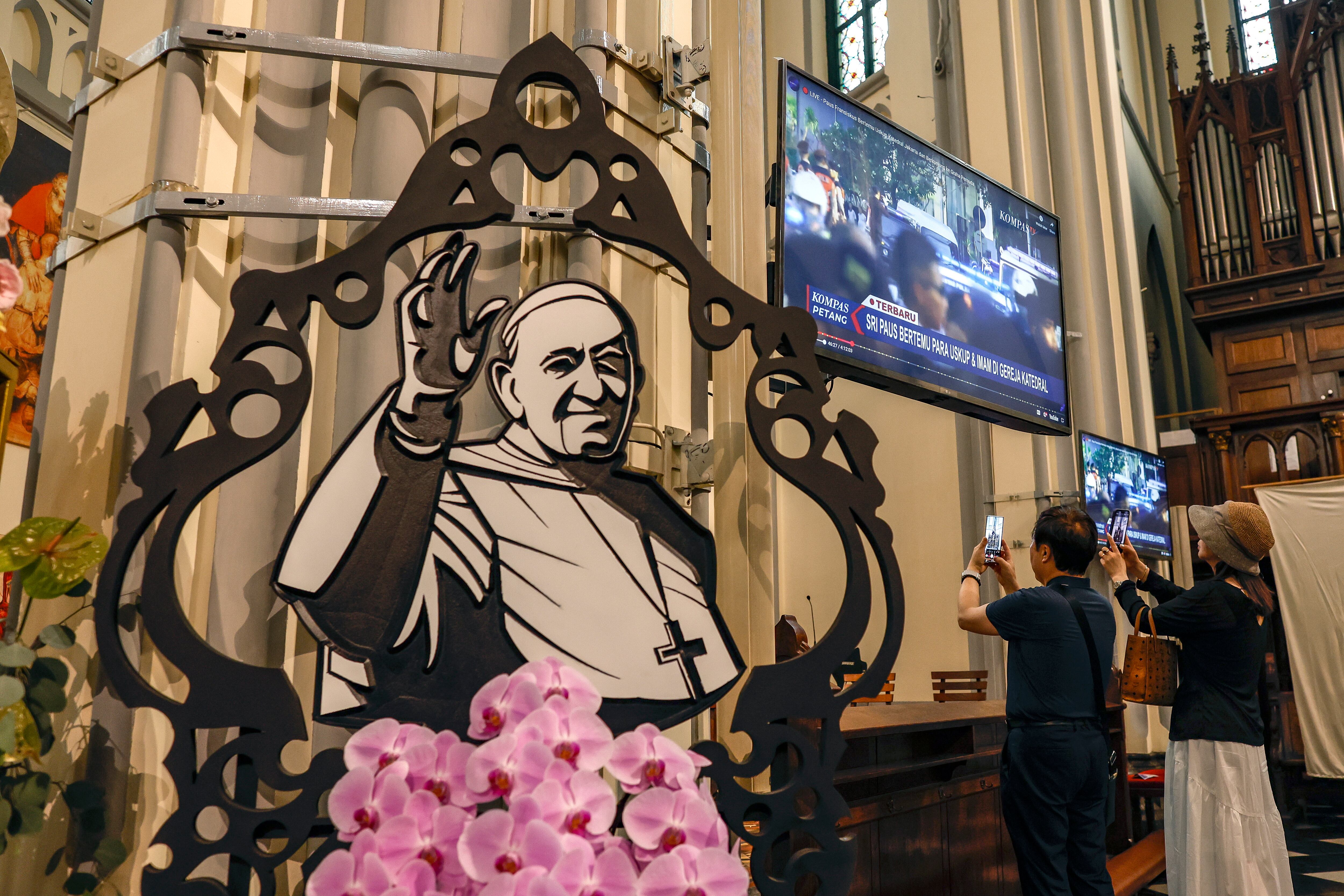 JAKARTA (Indonesia), 21/04/2025.- People take pictures with their mobile phones as a cut out picture of late Pope Francis is displayed inside the Cathedral of Our Lady of the Assumption in Jakarta, Indonesia, 21 April 2025. Pope Francis died on 21 April 2025 at the age of 88, according to the Holy See. Born Jorge Mario Bergoglio in Buenos Aires, Argentina, on 17 December 1936, he was appointed leader of the Catholic Church on 13 March 2013, succeeding Pontiff Emeritus Benedict XVI. (Papa, Santa Sede) EFE/EPA/MAST IRHAM