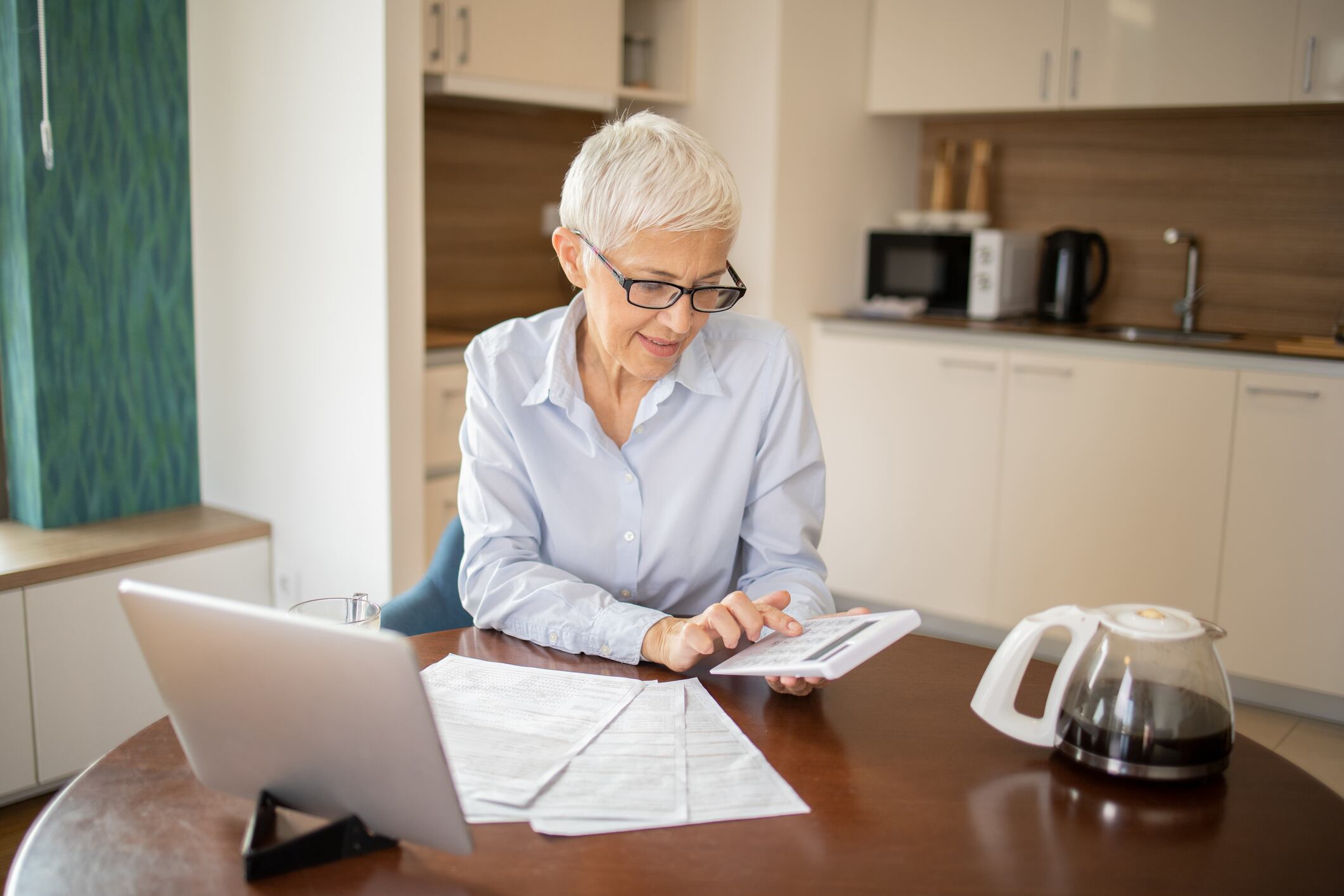 Mujer mayor haciendo cálculos sobre el computador (Getty Images)