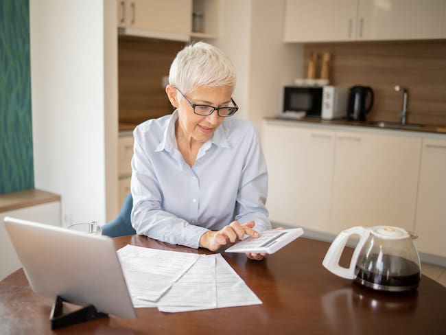 Mujer mayor haciendo cálculos sobre el computador (Getty Images)