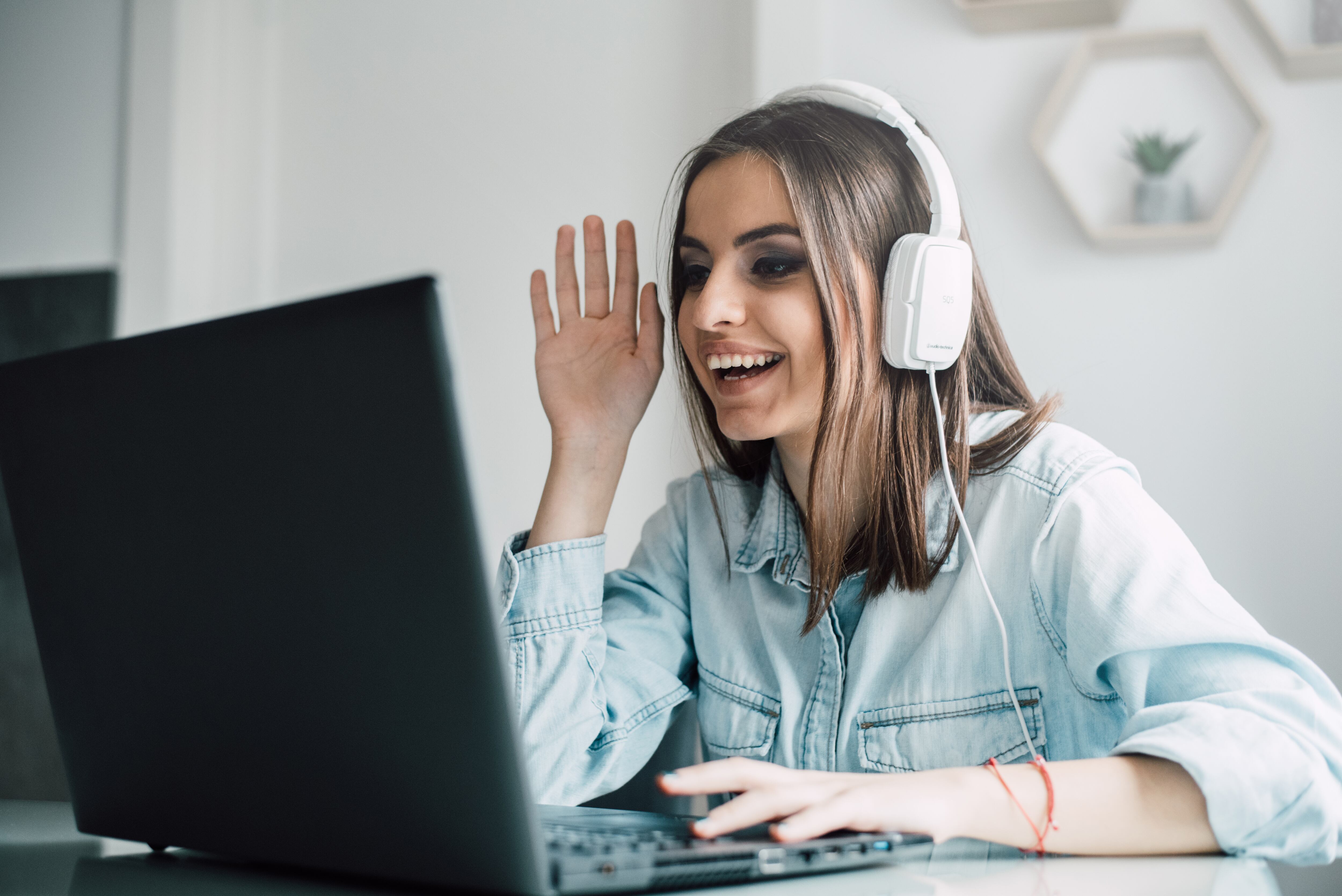 Mujer saludando durante una reunión virtual (Foto vía Getty Images)