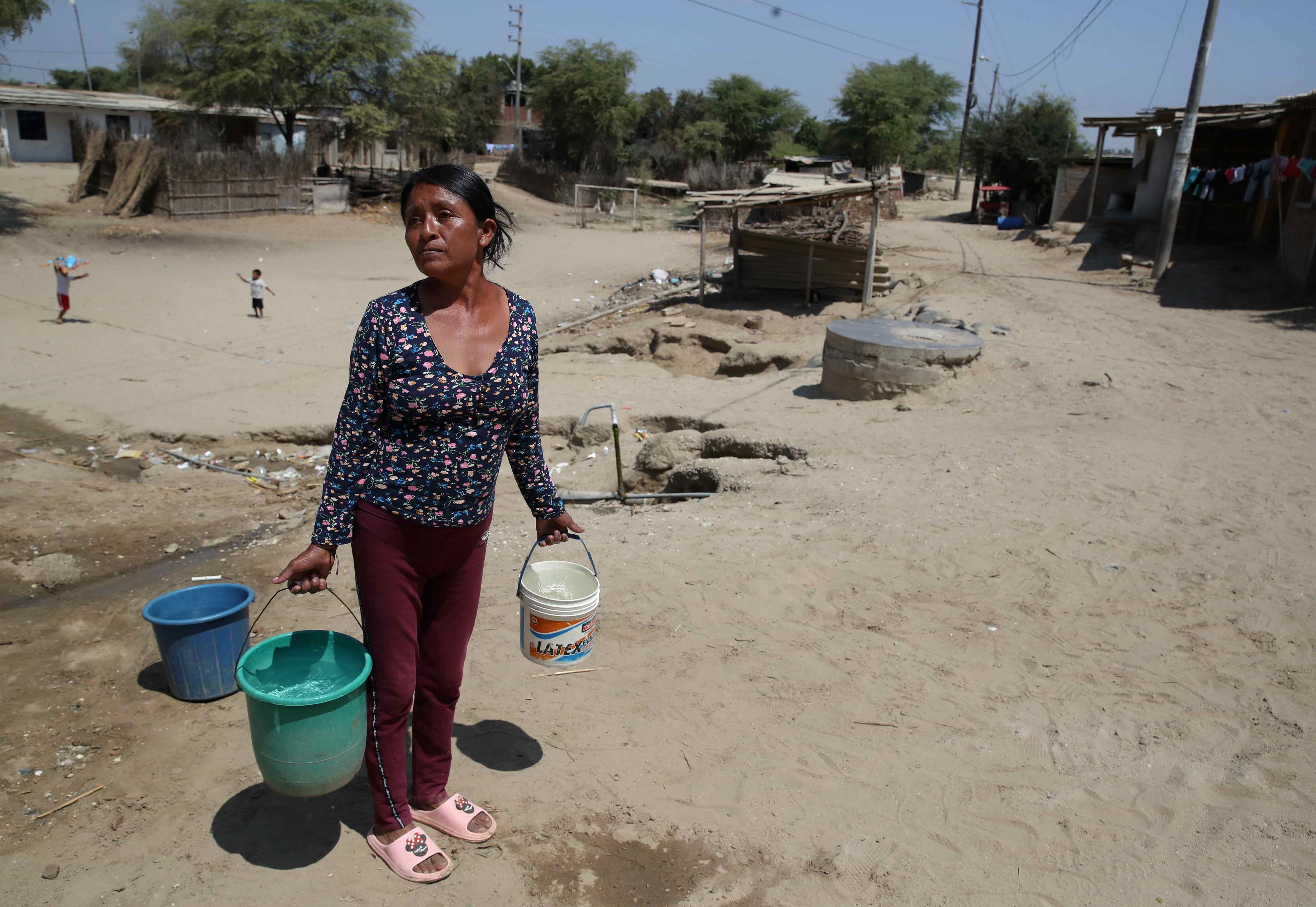 ACOMPAÑA CRÓNICA: PERÚ EL NIÑO*** AME713. MOCARÁ (PERÚ), 18/09/2023.- Una mujer carga baldes con agua de los bidones instalados por Acción contra el Hambre, el 6 de septiembre de 2023 en el asentamiento humano de Mocará, departamento de Piura (Perú). "El dengue mata", exclama un gran cartel en las puertas del cementerio de un asentamiento humano de la región de Piura, en el norte de Perú. Las muertes por esta enfermedad, que se han multiplicado por cinco este año respecto al anterior, son uno de los infinitos eslabones de la cadena de consecuencias de El Niño Costero, un fenómeno que hace más vulnerables a los vulnerables. EFE/Paolo Aguilar