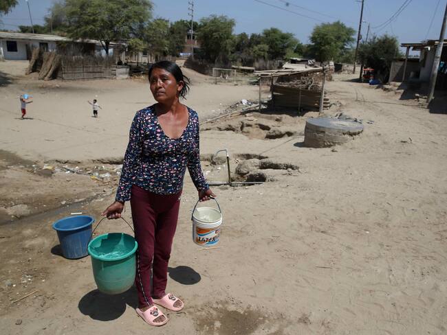ACOMPAÑA CRÓNICA: PERÚ EL NIÑO*** AME713. MOCARÁ (PERÚ), 18/09/2023.- Una mujer carga baldes con agua de los bidones instalados por Acción contra el Hambre, el 6 de septiembre de 2023 en el asentamiento humano de Mocará, departamento de Piura (Perú). &quot;El dengue mata&quot;, exclama un gran cartel en las puertas del cementerio de un asentamiento humano de la región de Piura, en el norte de Perú. Las muertes por esta enfermedad, que se han multiplicado por cinco este año respecto al anterior, son uno de los infinitos eslabones de la cadena de consecuencias de El Niño Costero, un fenómeno que hace más vulnerables a los vulnerables. EFE/Paolo Aguilar