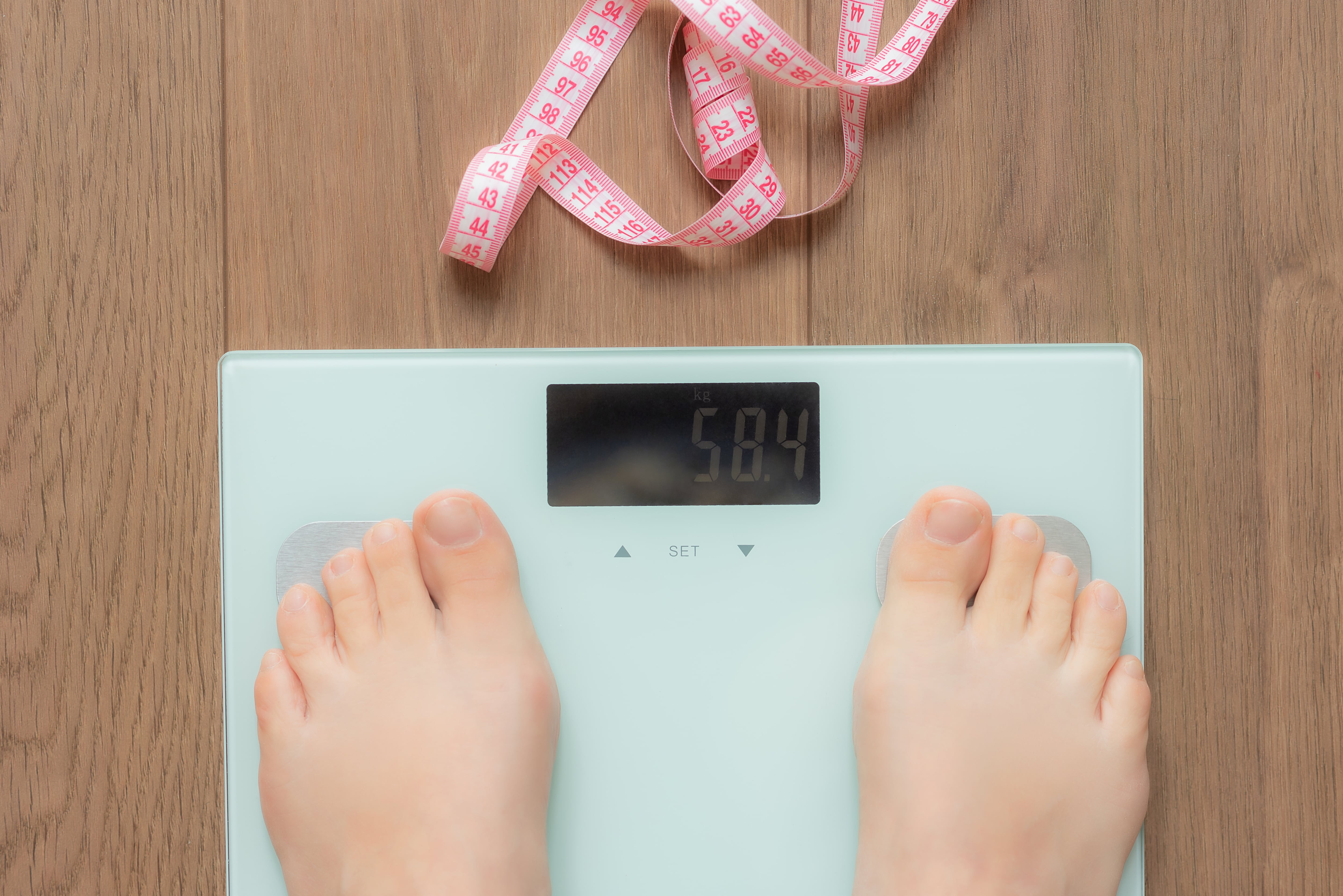 Persona sobre una báscula y un metro. (Foto: Getty Images)