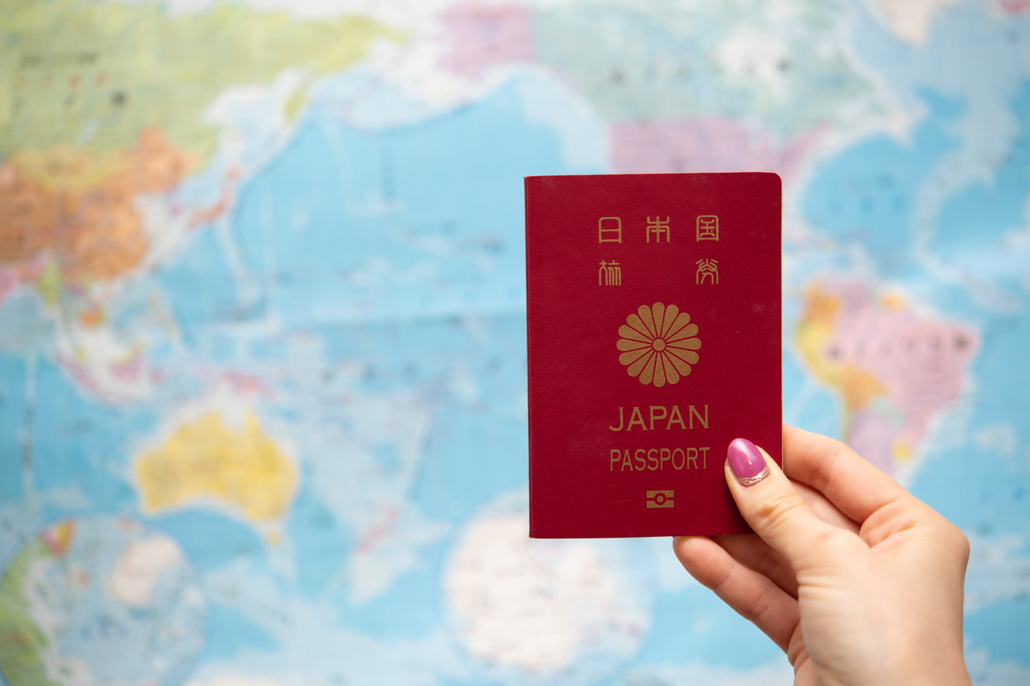 Mujer sosteniendo el pasaporte de Japón, teniendo de fondo un mapa del mundo (Getty Images)