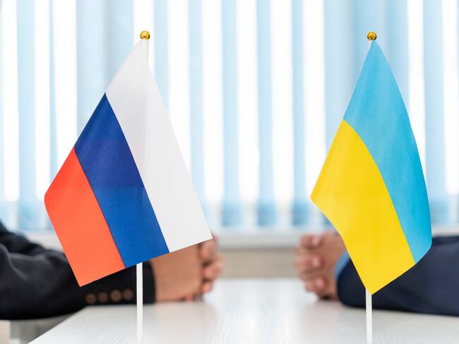 Close up Russian and Ukrainian flags. Diplomats negotiate on war between Russia and Ukraine. International relations. Conflict settlement and negotiations. Diplomacy. Stop war.