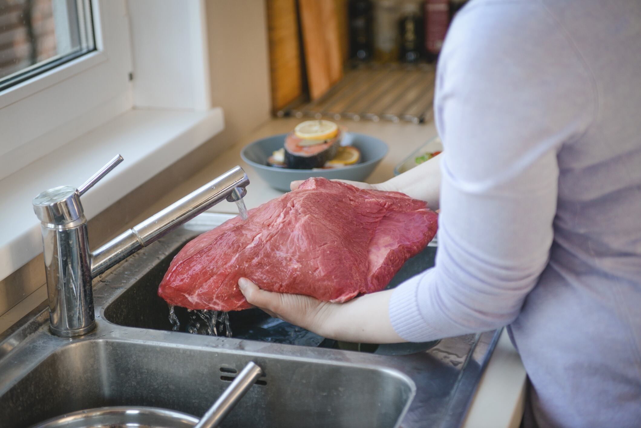 Mujer lavando la carne // Getty Images