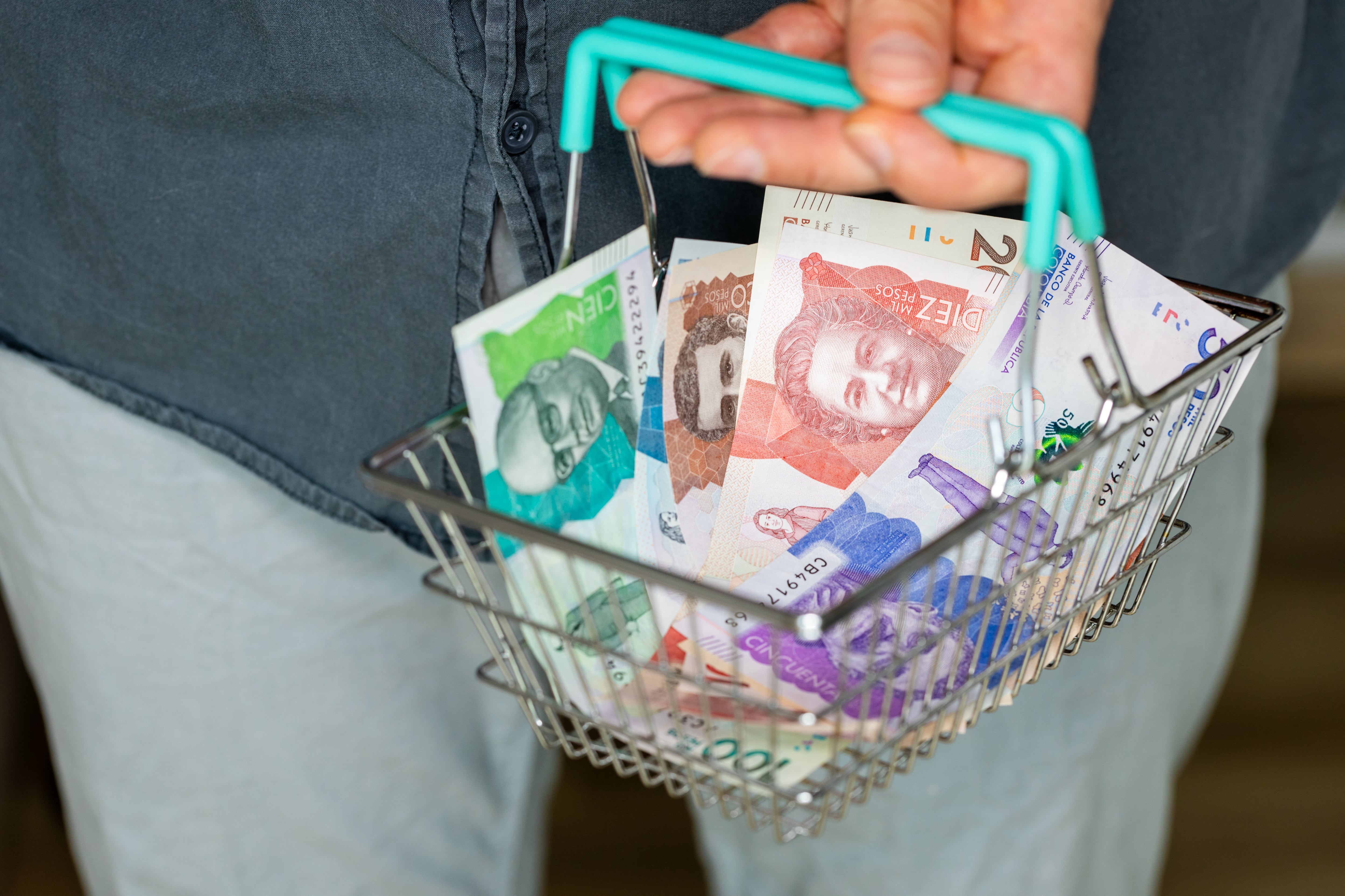 Persona sosteniendo una canasta con dinero colombiano. (Foto: Getty Images)