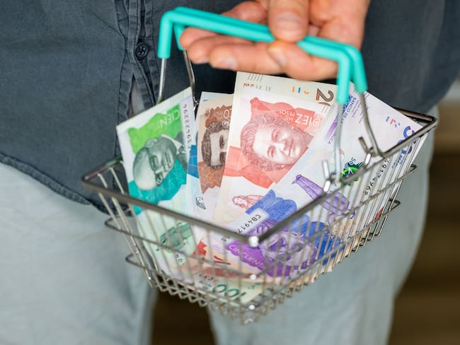 Persona sosteniendo una canasta con dinero colombiano. (Foto: Getty Images)