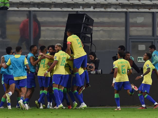 Brazilian players celebrate a goal scored by teammate defender Marquinhos (covered) during the 2026 FIFA World Cup South American qualifiers football match between Peru and Brazil, at the Nacional stadium in Lima, on September 12, 2023. (Photo by CRIS BOURONCLE / AFP) (Photo by CRIS BOURONCLE/AFP via Getty Images)