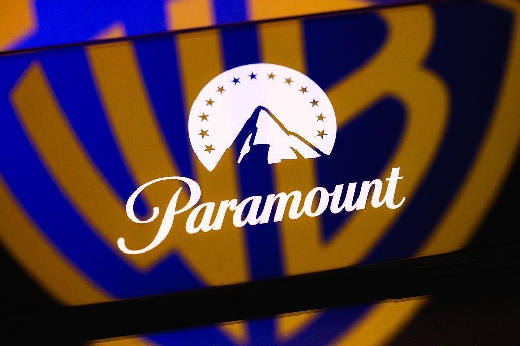 The Paramount logo is displayed on a smartphone screen placed on a reflective surface onto which the Warner Bros. logo is projected, in Creteil, France, on September 22, 2026, as Paramount Skydance reaches a settlement with the 12 state attorneys general who challenged its acquisition of Warner Bros. Discovery. (Photo by Samuel Boivin/NurPhoto via Getty Images)