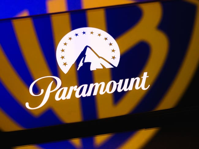 The Paramount logo is displayed on a smartphone screen placed on a reflective surface onto which the Warner Bros. logo is projected, in Creteil, France, on September 22, 2026, as Paramount Skydance reaches a settlement with the 12 state attorneys general who challenged its acquisition of Warner Bros. Discovery. (Photo by Samuel Boivin/NurPhoto via Getty Images)