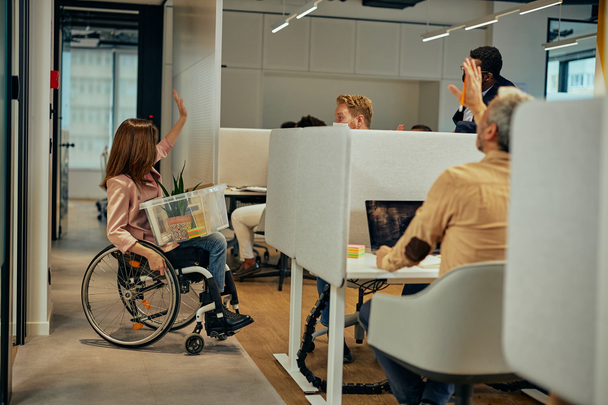 Mujer con situación de discapacidad despidiéndose de sus compañeros de trabajo (Getty Images)