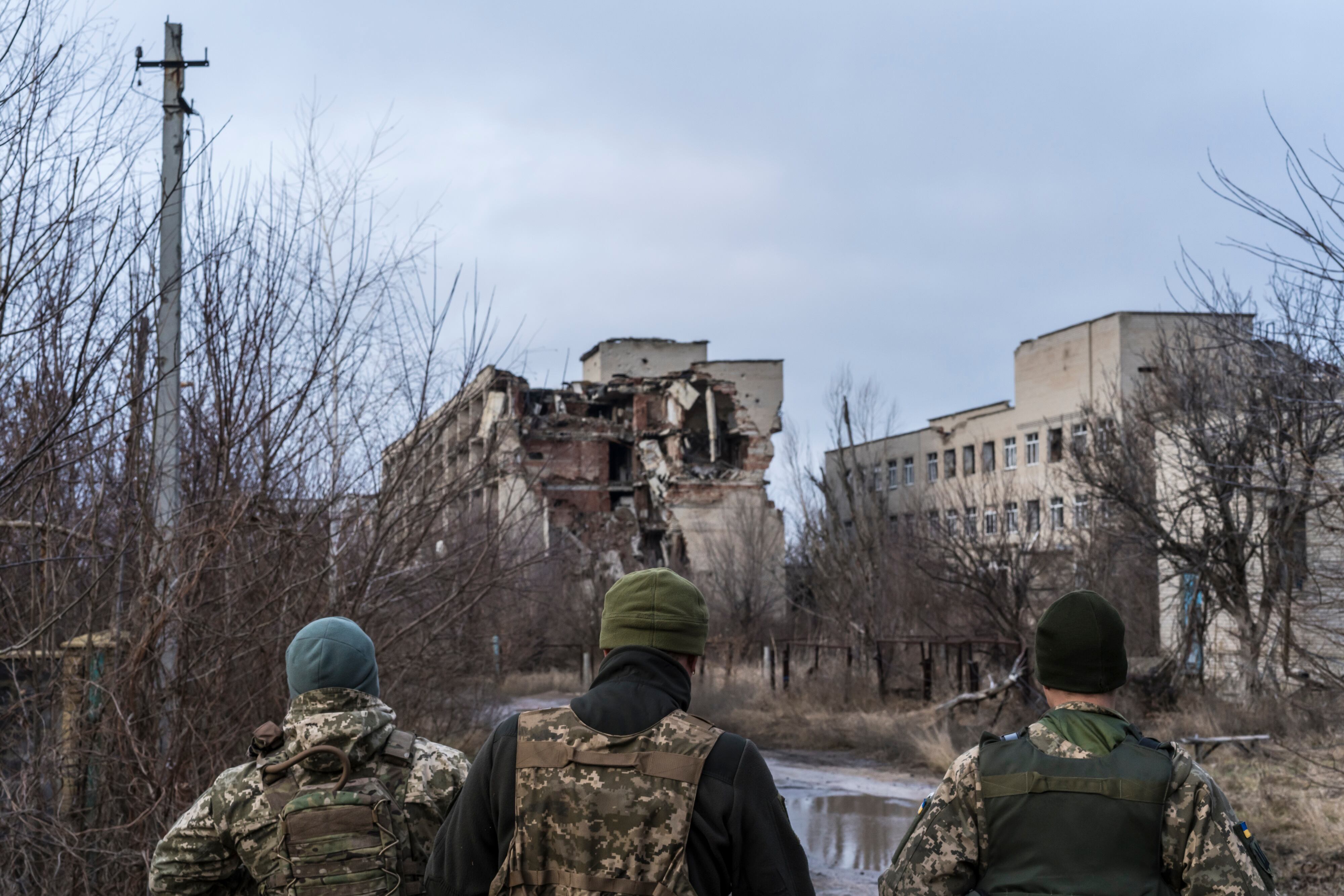 MARINKA, UKRAINE - DECEMBER 8: Ukrainian soldiers walk past destroyed buildings on the front line on December 8, 2021 in Marinka, Ukraine. A build-up of Russian troops along the border with Ukraine has heightened worries that Russia intends to invade the Donbas region, most of which is held by separatists after a 7-year-long war with the Ukrainian government. On Tuesday, U.S. President Joe Biden met with Russian President Vladimir Putin via video conference to discuss the escalation tensions. (Photo by Brendan Hoffman/Getty Images)