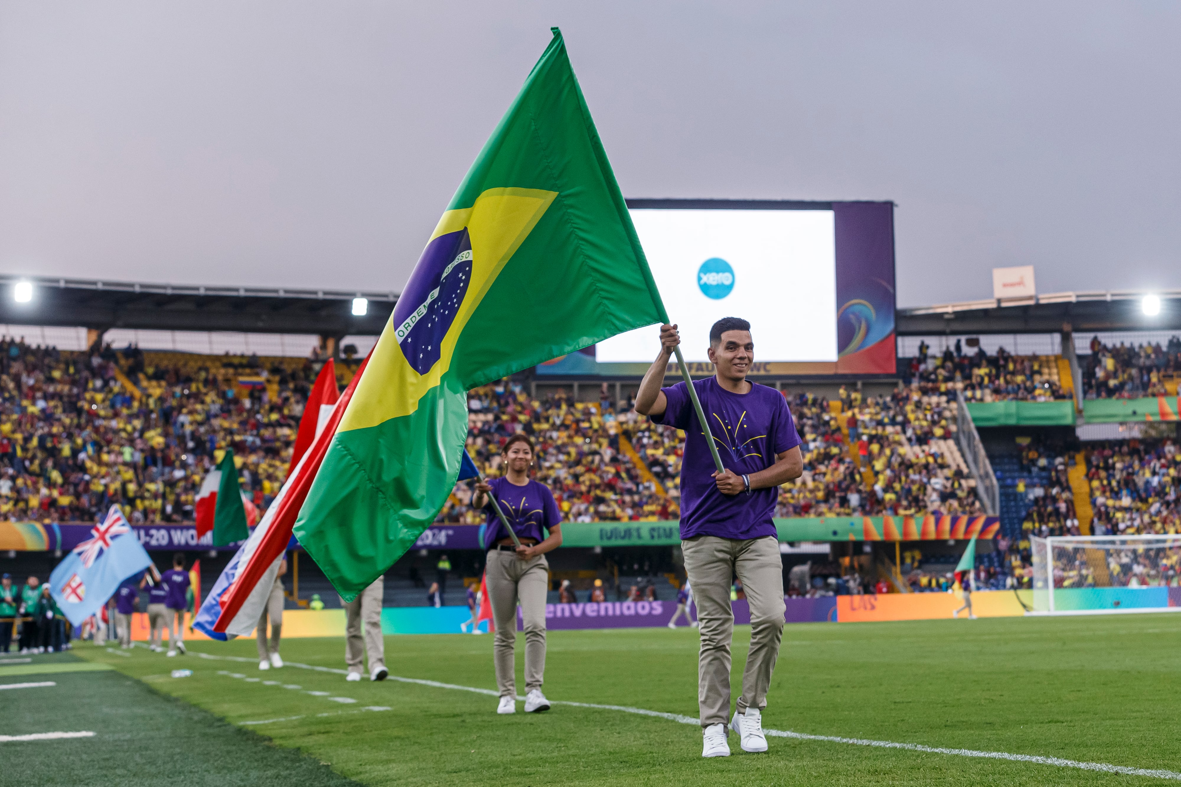 BOGOTA, COLOMBIA - AUGUST 31: Volunteer enters the pitch with the flag of Brazil prior to the Group A match between Colombia and Australia as part of FIFA U-20 Women's World Cup Colombia 2024 at Estadio El Campin on August 31, 2024 in Bogota, Colombia. (Photo by Martín Fonseca/Eurasia Sport Images/Getty Images)