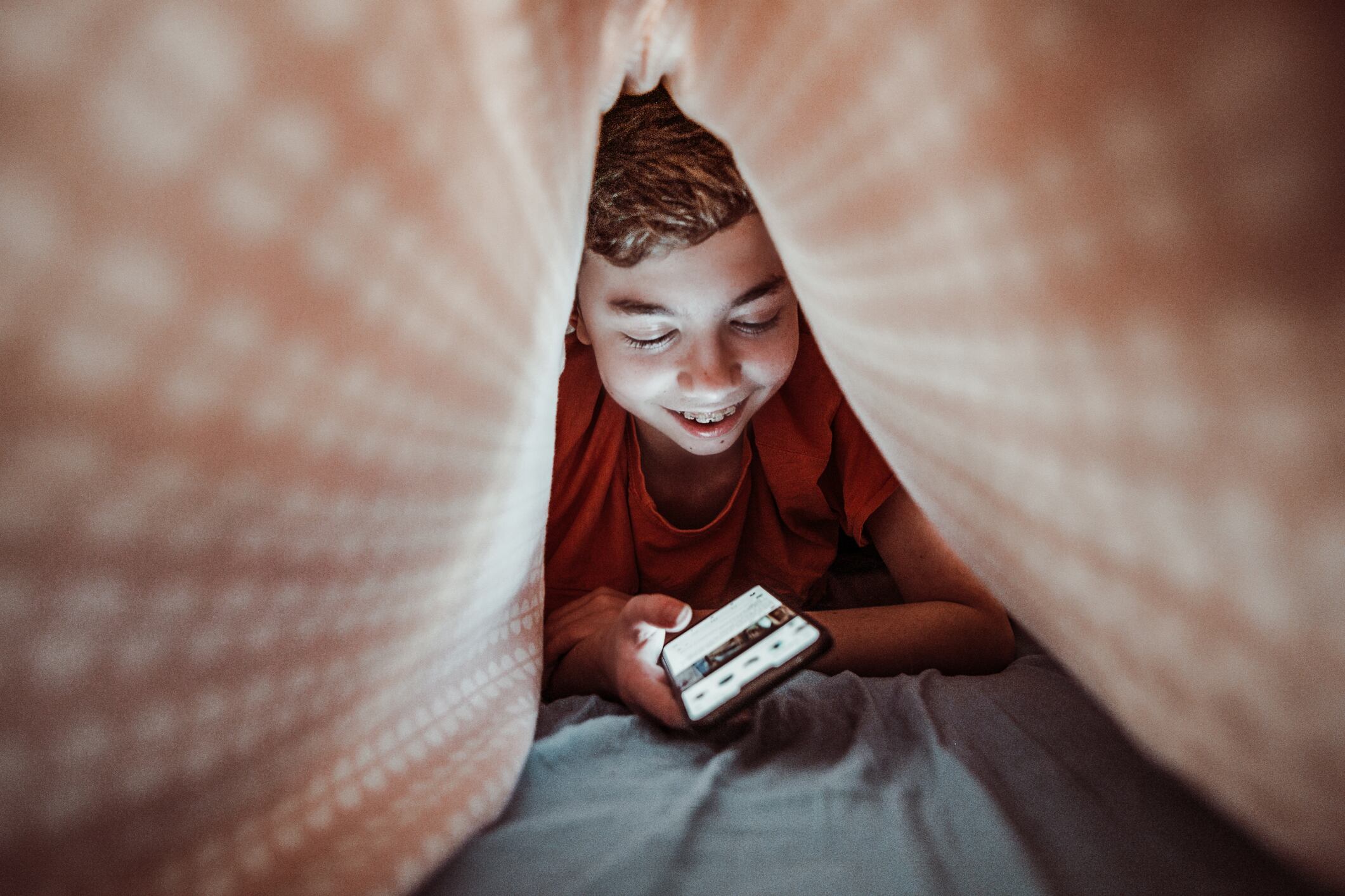 boy teenager in bed texting with smartphone at night