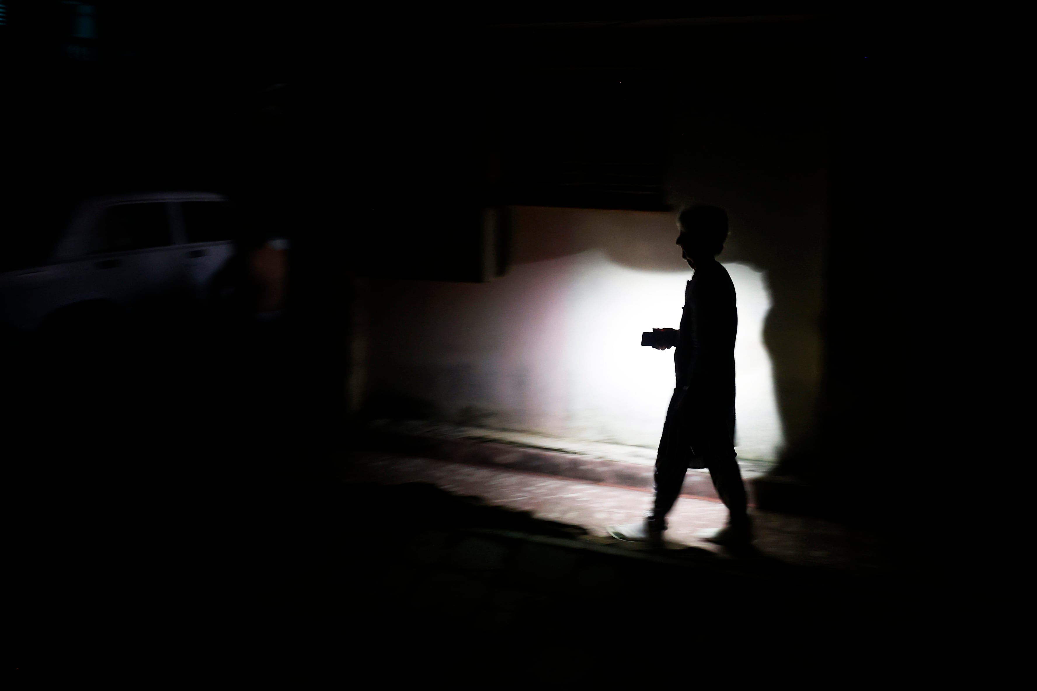 ACOMPAÑA CRÓNICA CUBA APAGONES AME8952. LA HABANA (CUBA), 19/10/2024.- Una persona camina durante un apagón este viernes, en La Habana, (Cuba). Cuando de verdad se sufre el apagón es de noche. Cuando las casas quedan totalmente a oscuras, las cocinas eléctricas no sirven para preparar la cena, los ventiladores inertes no espantan el calor caribeño y sólo las luces de un carro o un celular rompen el negro más rotundo. EFE/ Ernesto Mastrascusa