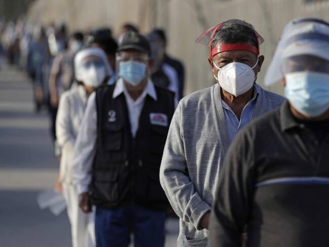 Ciudadanos hacen fila para votar hoy en un centro electoral en el distrito de Villa El Salvador, en Lima