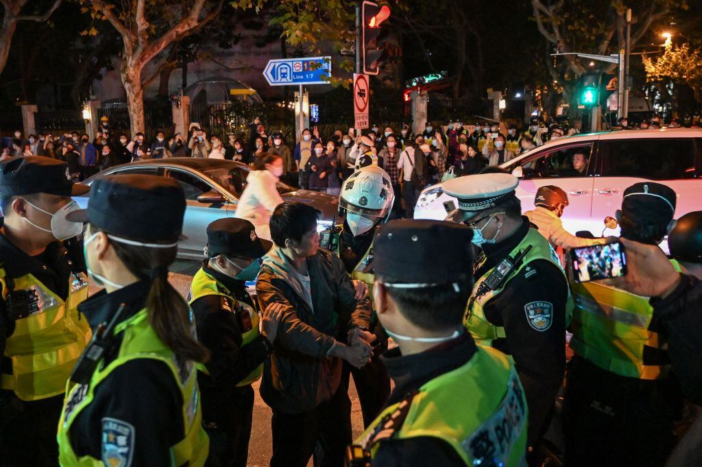 Police officers confront a man as they block Wulumuqi street, named for Urumqi in Mandarin, in Shanghai on November 27, 2022, in the area where protests against China's zero-Covid policy took place the night before following a deadly fire in Urumqi, the capital of the Xinjiang region. (Photo by Hector RETAMAL / AFP) (Photo by HECTOR RETAMAL/AFP via Getty Images)