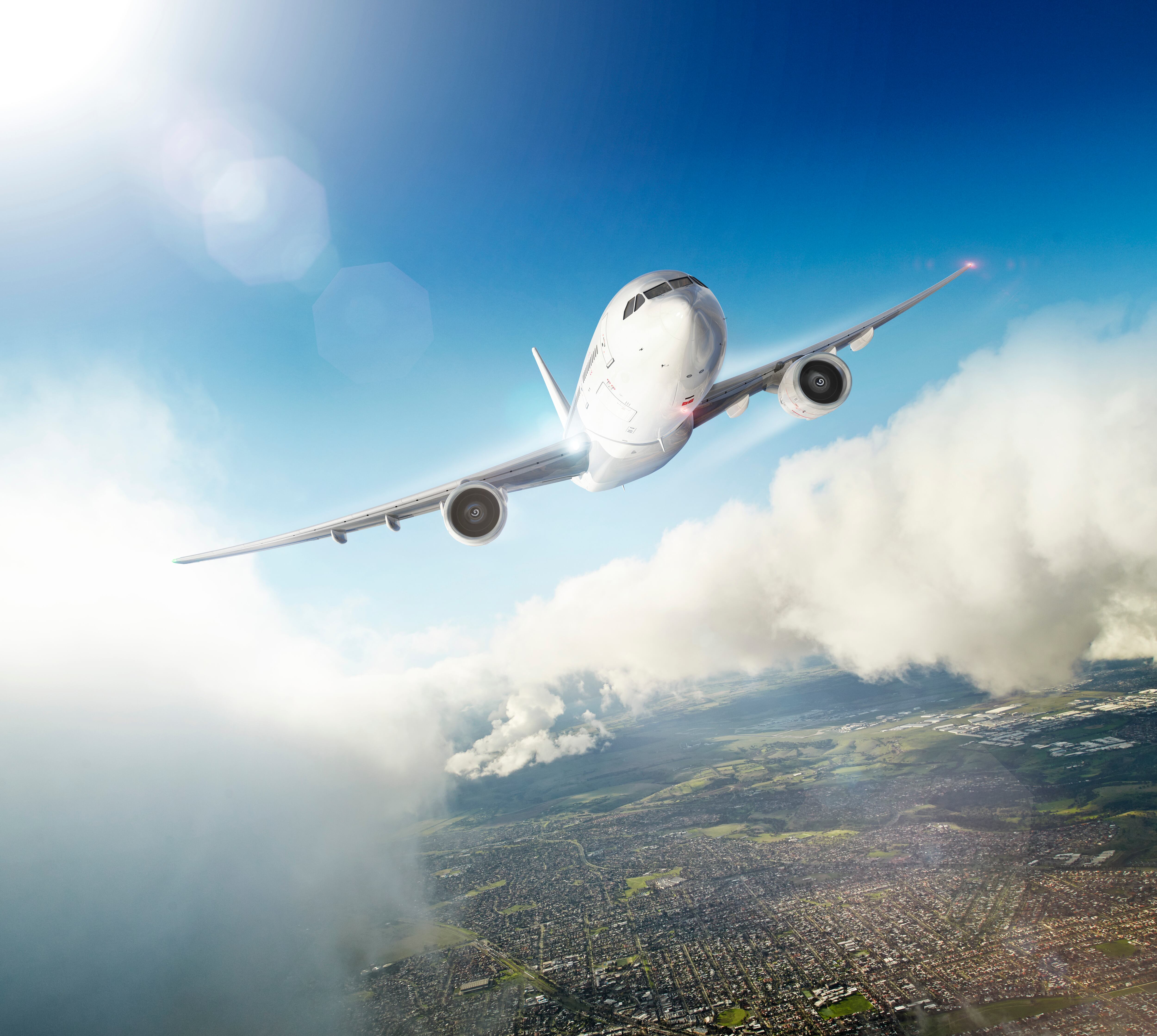Avión volando sobre una ciudad y atravesando las nubes (Foto vía GettyImages)